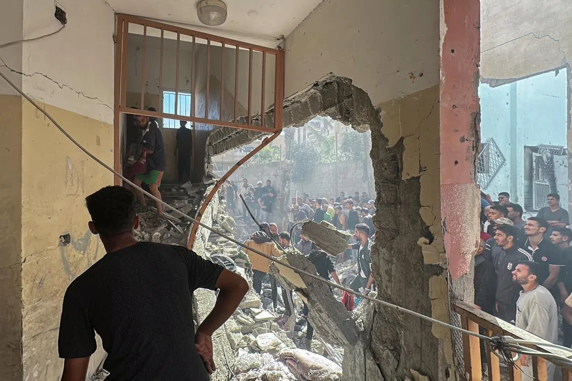 Palestinians inspect the site of an Israeli strike on a school sheltering displaced people, amid the Israel-Hamas conflict, in Nuseirat in the central Gaza Strip October 24, 2024. REUTERS/Khamis Al-Rifi