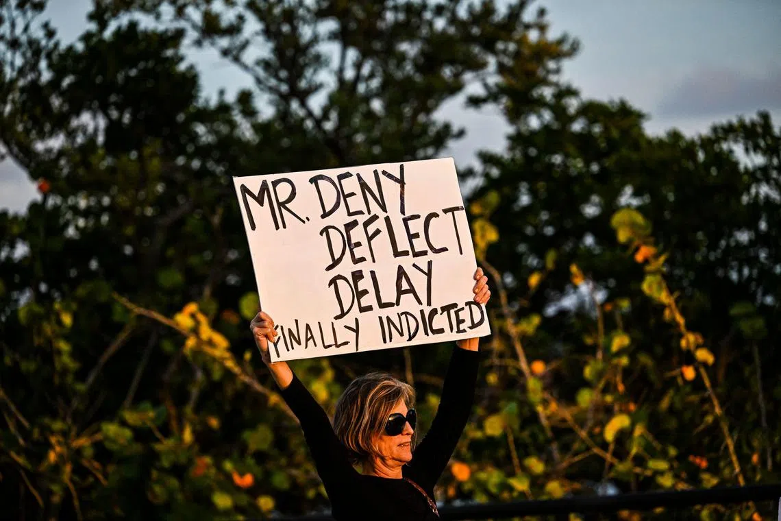 A woman holds an sign approving the indictment of US President Donald Trump near the Mar-a-Lago Club in Palm Beach, Florida, on March 31, 2023. - A New York grand jury has voted to indict former US president Donald Trump over hush money payments made to porn star Stormy Daniels ahead of the 2016 election, multiple US media reported on March 30, 2023. (Photo by CHANDAN KHANNA / AFP)