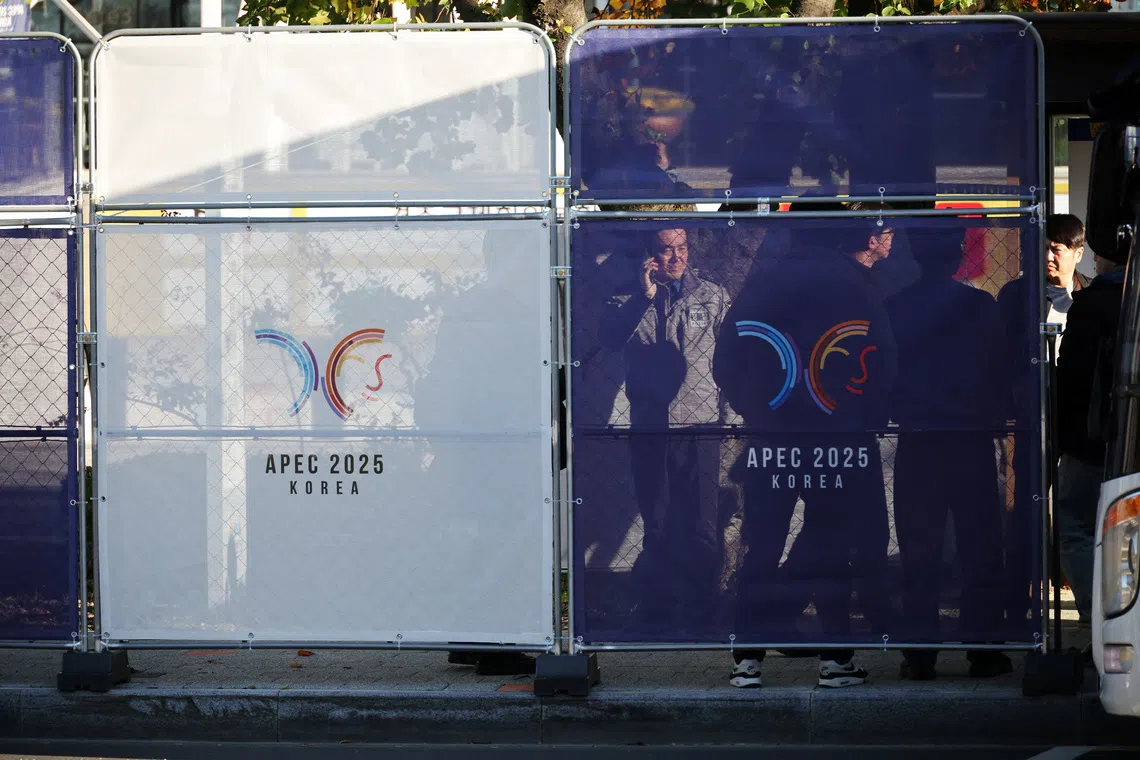 People stand behind fences bearing the logo of 2025 Asia-Pacific Economic Cooperation leaders' summit, at the venue for the summit in Gyeongju, South Korea, October 28, 2025.   REUTERS/Kim Hong-Ji