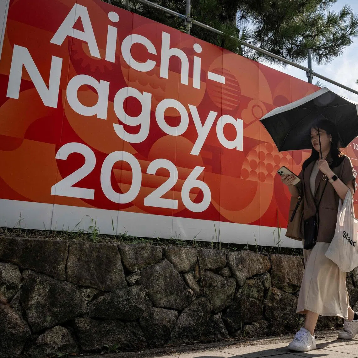 This picture taken on September 8, 2025, shows a woman walking past an advertisement for the 2026 Aichi-Nagoya Asian Games in Nagoya, Aichi prefecture. The Games will take place from Sept 19 to Oct 4, 2026.