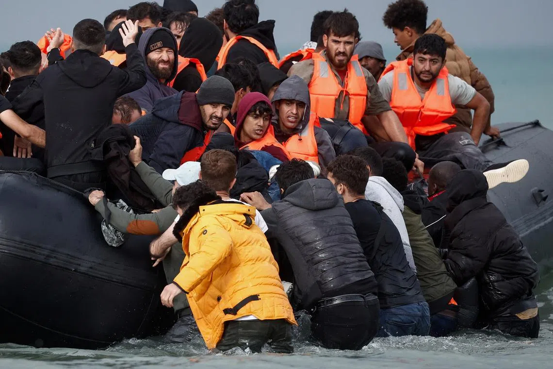 Migrants attempting to cross the English Channel to reach Britain get on an inflatable dinghy as the French police and gendarmes officers patrol on the beach of the Slack dunes in Wimereux, France, September 4, 2024. REUTERS/Benoit Tessier