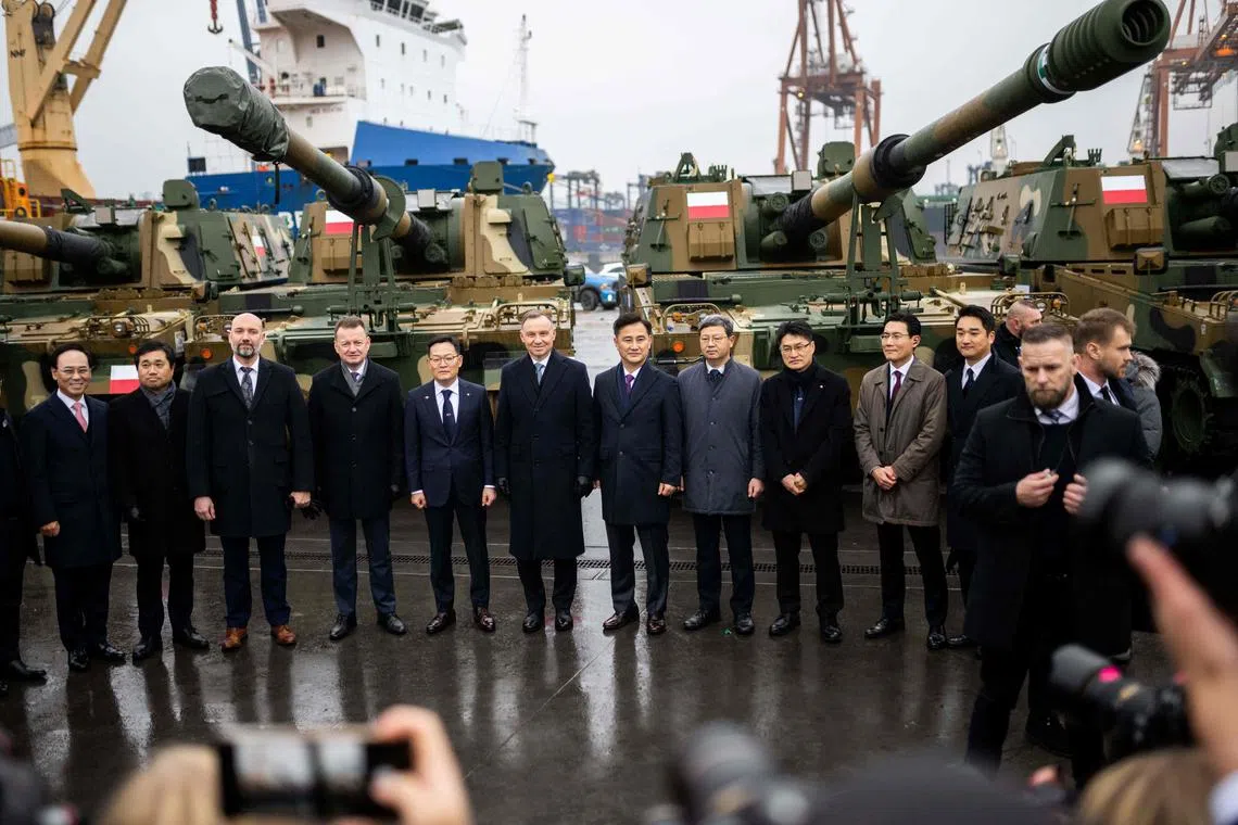 Polish President Andrzej Duda (6L), Minister of South Korea's state arms procurement agency Eom Donghwan (7L) and Polish Defence Minister Mariusz Blaszczak (4L) pose with officials during the acceptance of the first South Korean K2 battle tanks and South Korean K9 howitzers for Poland in December 6, 2022 at the Baltic Container Terminal in Gdynia. - The Polish Army is strengthening its potential with the use of South Korean defense technologies. In July this year an agreement was concluded with Hyundai Rotem for the acquisition of a total of 1,000 K2 tanks with accompanying vehicles. (Photo by MATEUSZ SLODKOWSKI / AFP)