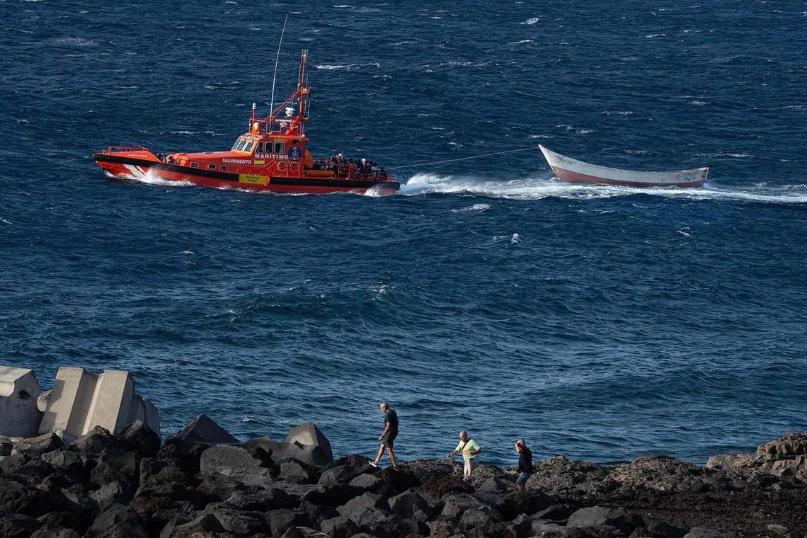 TOPSHOT - Spanish Salvamento Maritimo (Sea Search and Rescue agency) vessel "Salvamar Adhara" tows a boat after rescuing the 63 migrant people who were drifting without propulsion off the the coast of La Restinga port, where they were eventually brought to shore, on the Canary island of El Hierro on August 21, 2024. The number of migrants reaching the Canary Islands more than doubled in the first 7.5 months of 2024. Figures show that 22,304 migrants reached the Atlantic archipelago in the period to August 15, up from 9,864 in the same period a year earlier, interior ministry numbers show. The figure represents a 126-percent increase year on year. (Photo by Antonio Sempere / AFP)