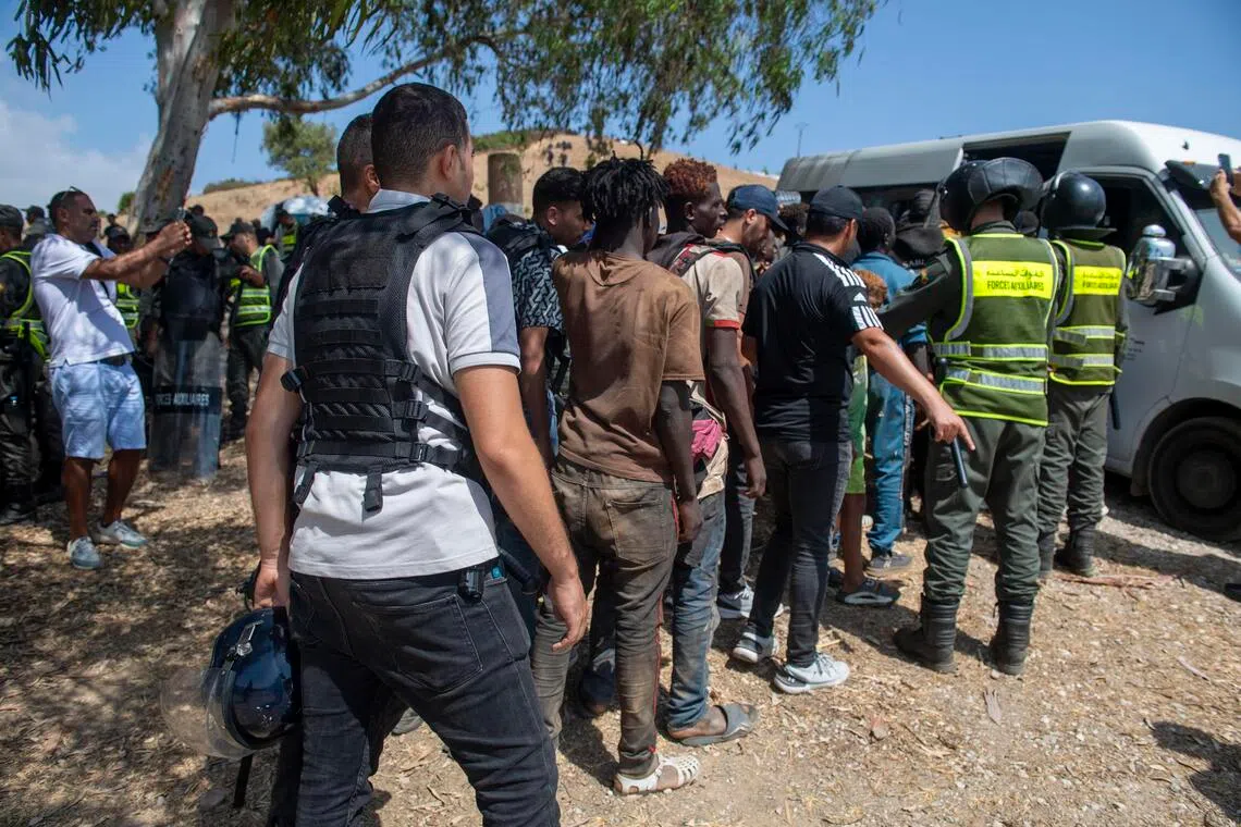 Moroccan security forces arresting migrants trying to enter the north African Spanish enclave of Ceuta on Aug 15. Hundreds of sub-Saharan African and Sudanese migrants gathered near Fnideq, Morocco, to try to enter Ceuta from Morocco.