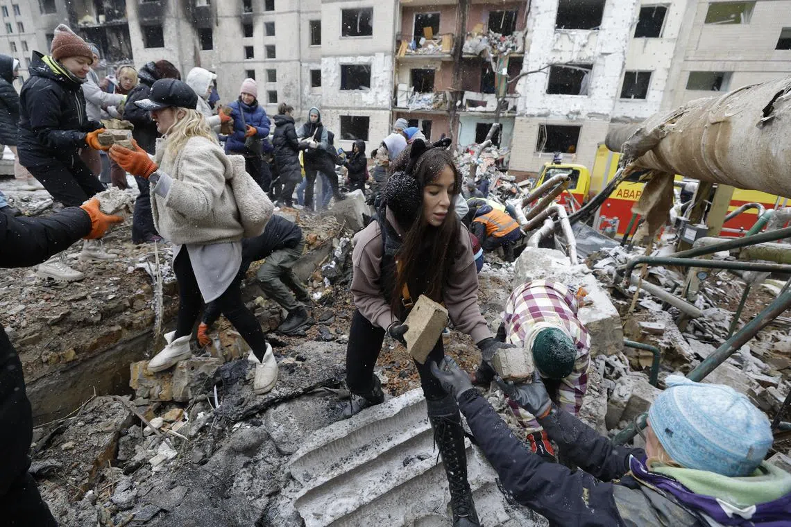 Ukrainian volunteers remove debris from the site of a damaged building, a day after a Russian missile strike, in Kyiv.