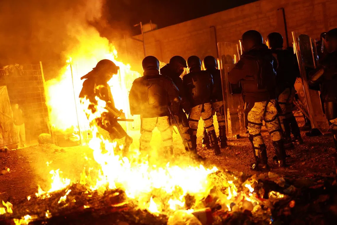 Members of the Mexican National Guard in riot gear take part in an operation to remove migrants from a camp, as migrants burn their belongings, in Chihuahua, Chihuahua state, Mexico January 18, 2025. REUTERS/Jose Luis Gonzalez