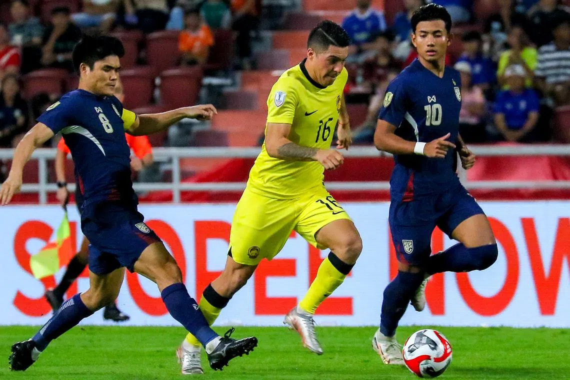 Malaysia's Sergio Aguero driving forward despite the attention of Thailand's Peeradol Chamrasamee (left) and Suphanat Mueanta during their 1-0 defeat by the Thais in an Asean Championship Group A match in Bangkok on Dec 14.