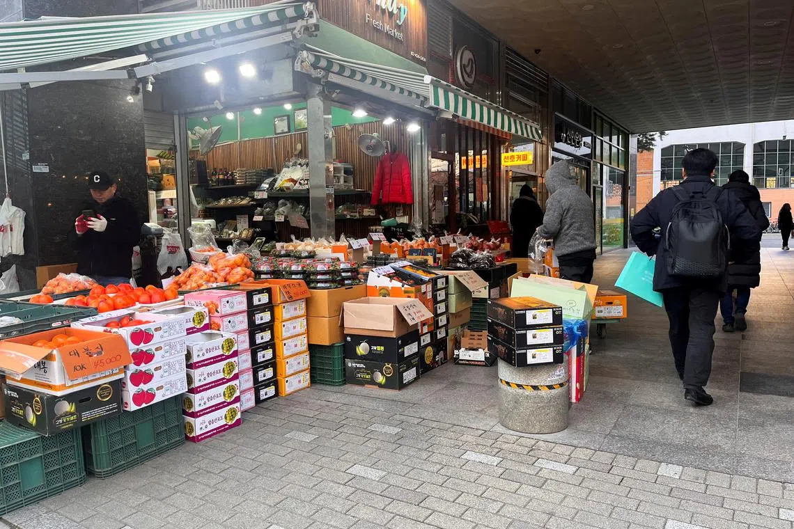 FILE PHOTO: People walk next to a fresh produce stall, in Seoul South Korea December 4, 2024. REUTERS/Ju-min Park/File Photo