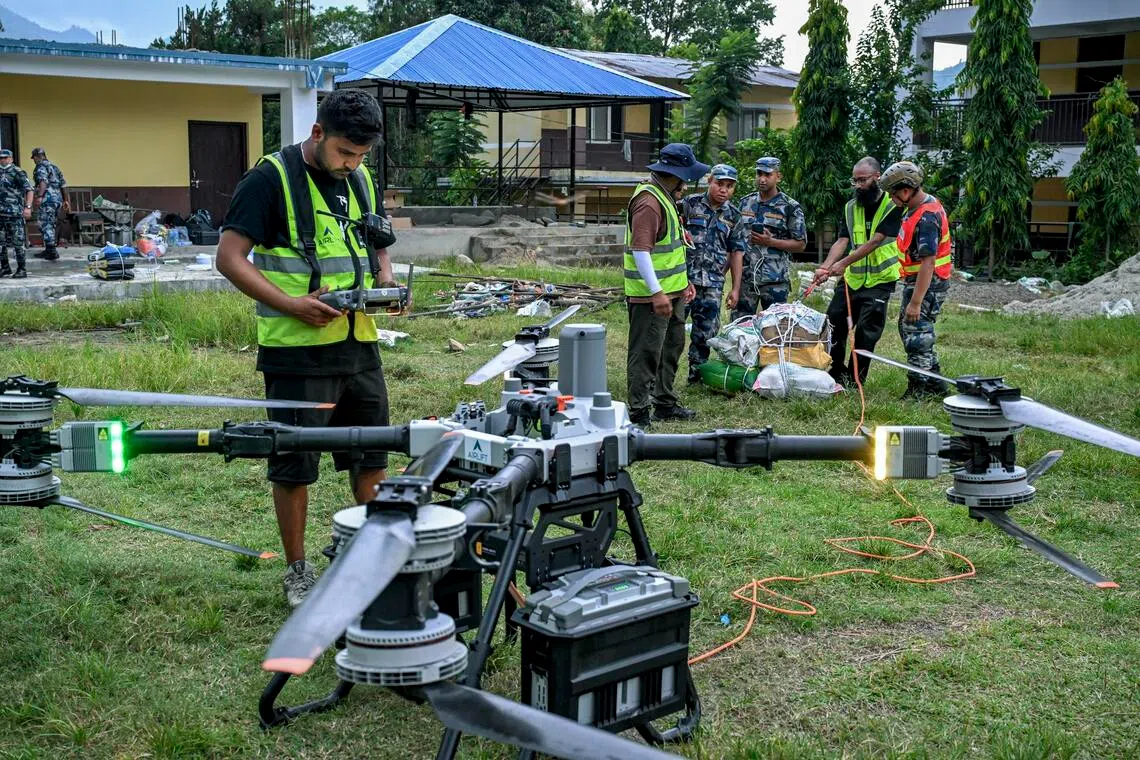 Volunteers work with police to pack essential food, medicine, and other supplies for a drone relief operation at Devighat, Nepal.