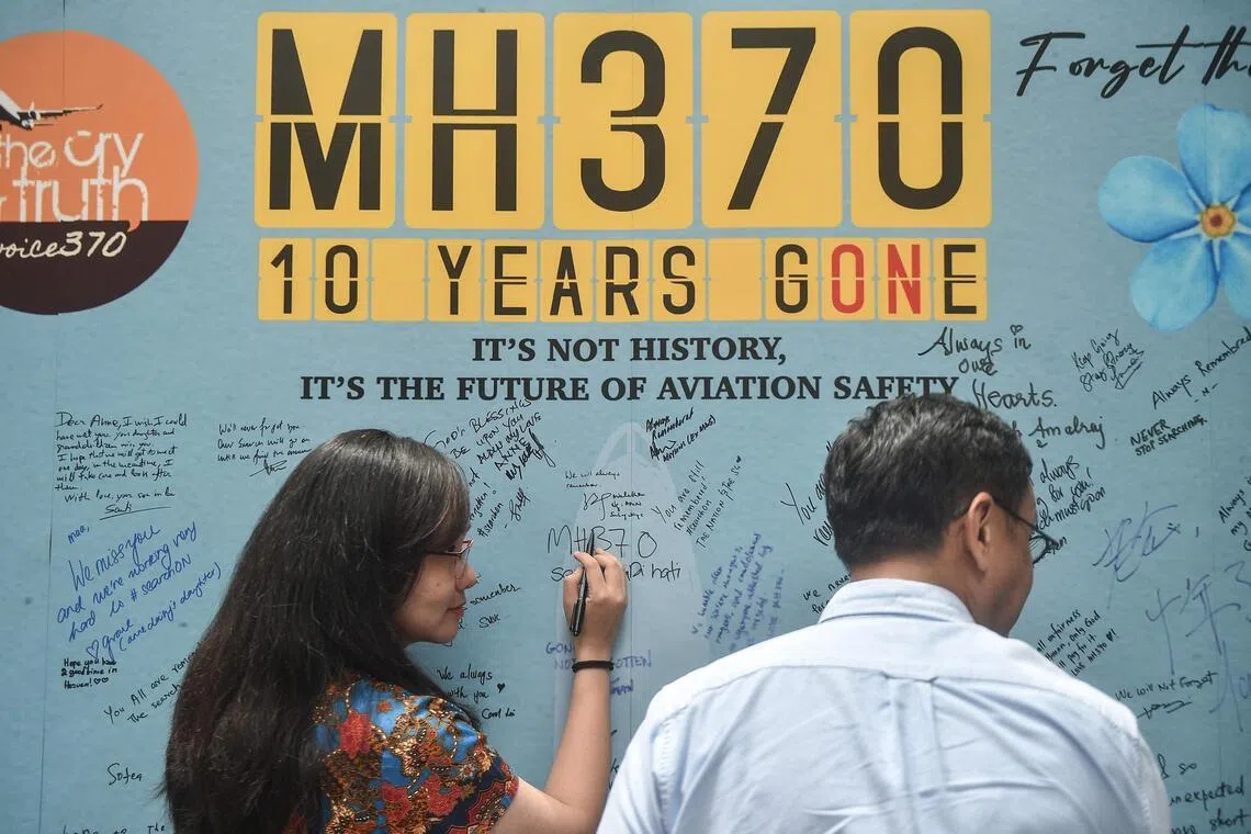 A March 2024 photo shows a woman writing a message to mark the 10th year since Malaysia Airlines flight MH370 carrying 239 people disappeared from radar screens while en route from Kuala Lumpur to Beijing.