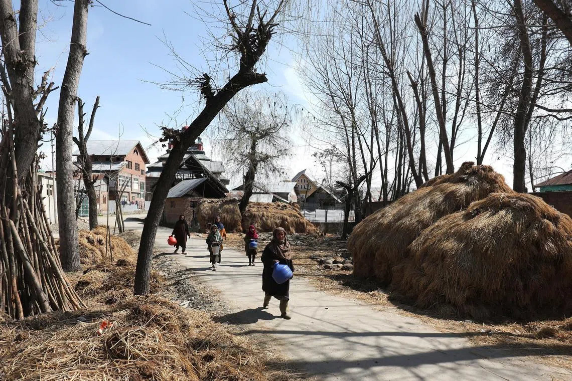 Kashmiri women walking to fill their pots with water from a river in the village of Pattan, some 22 km north of Srinagar, Kashmir, India, on March 18, 2024. 