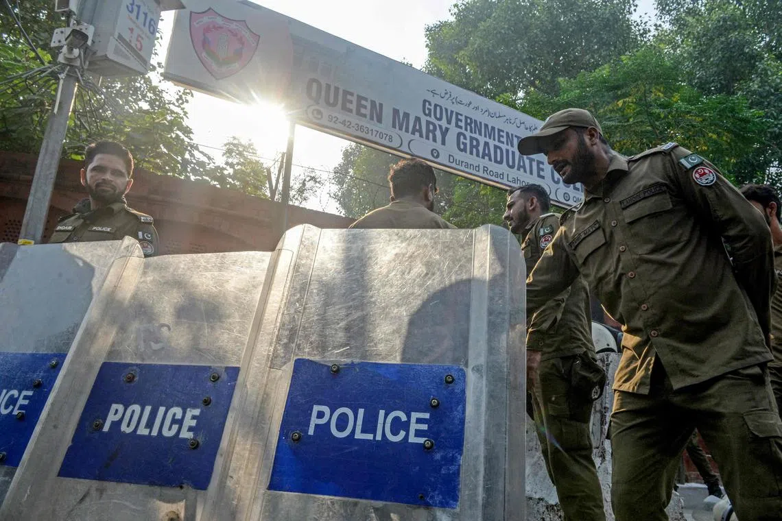 Policemen stand guard outside a closed college amid ongoing protests over an alleged rape of a woman student.