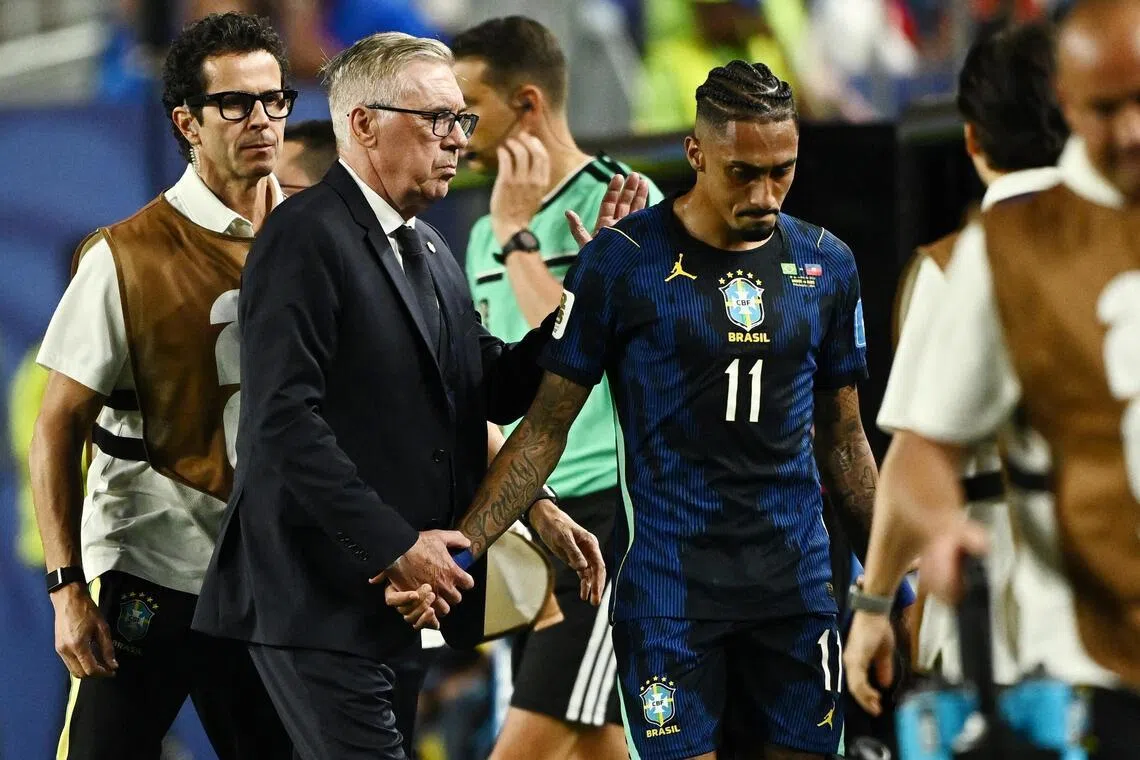 Brazil coach Carlo Ancelotti consoles Raphinha as he walks off the pitch after sustaining an injury.