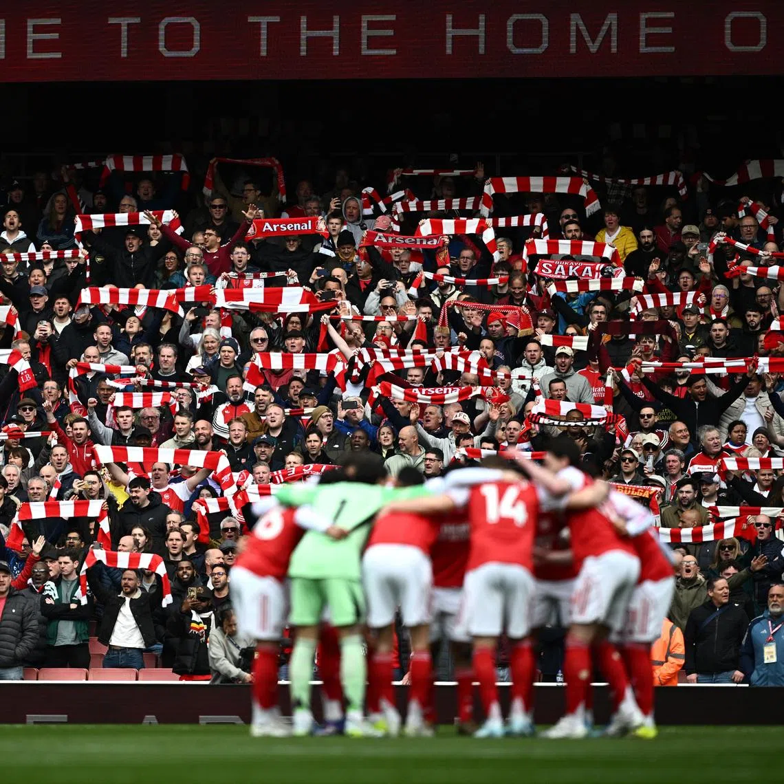 Soccer Football - Premier League - Arsenal v AFC Bournemouth - Emirates Stadium, London, Britain - April 11, 2026 Arsenal fans holds scarves up inside the stadium as Arsenal players huddle before the match REUTERS/Dylan Martinez