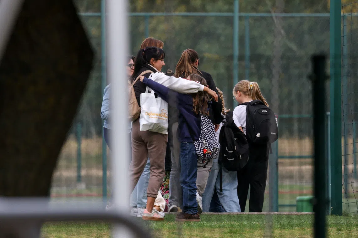 A woman embraces a child, as emergency services (not pictured) work at the site of a deadly attack at a school by a 15-year-old former pupil, in Leszczydol-Nowiny, Wyszkow County, north-east of Warsaw, Poland, on Oct 8.