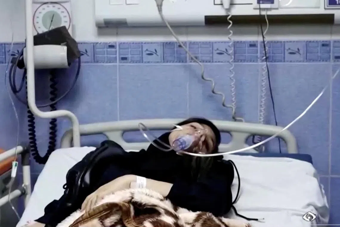A young woman lies in hospital after reports of poisoning at an unspecified location in Iran, in a still image from video.