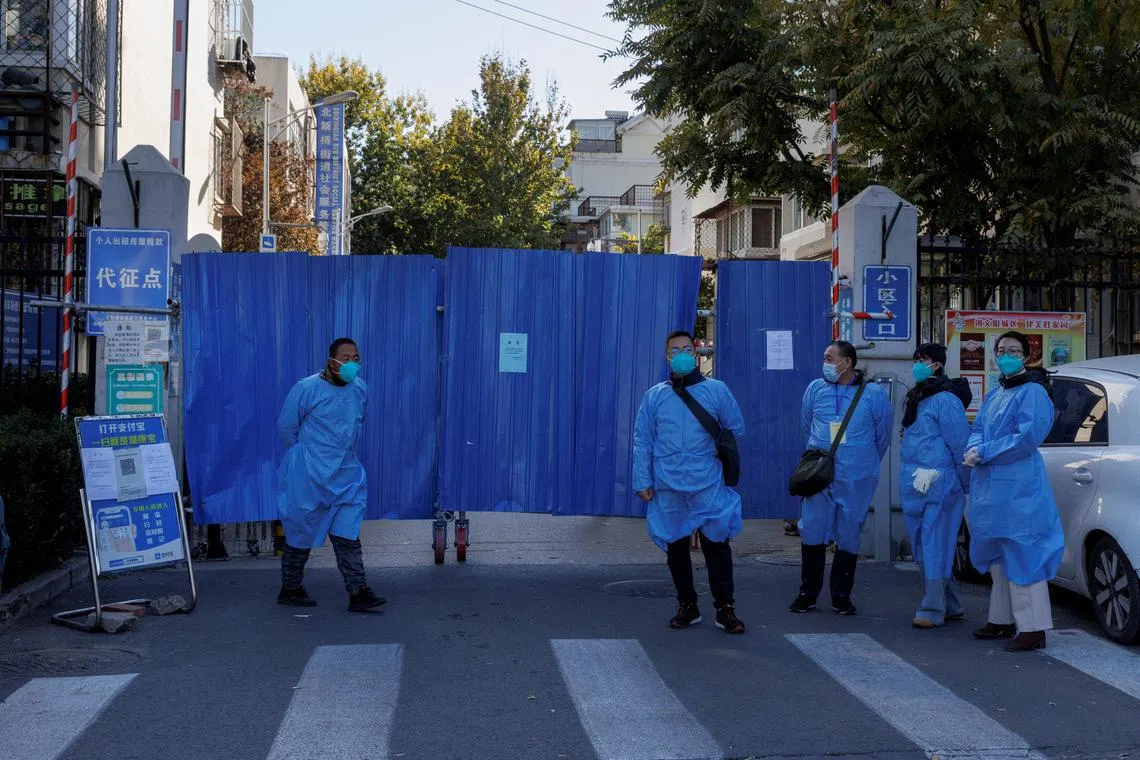Officials wearing protective aprons at gate of a residential compound placed under lockdown in Beijing, on Nov 7, 2022.