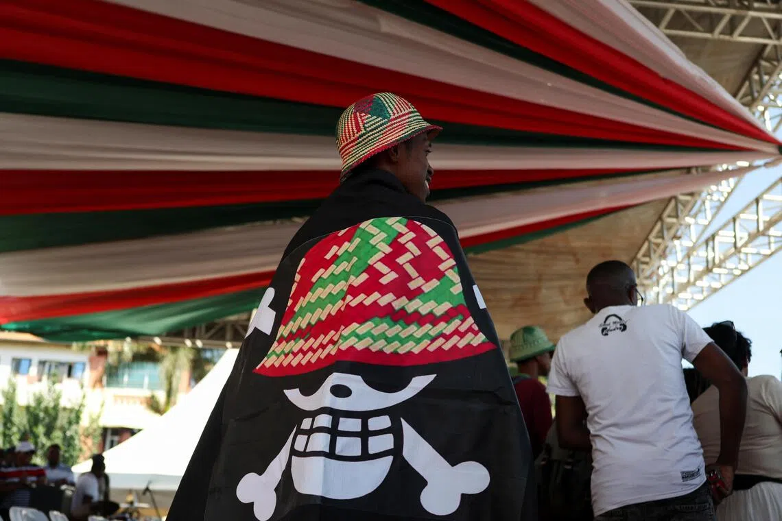 A protester covers himself with a banner featuring a Malagasy version of the logo from the popular Japanese manga One Piece, a symbol adopted by Gen Z protest movements worldwide.