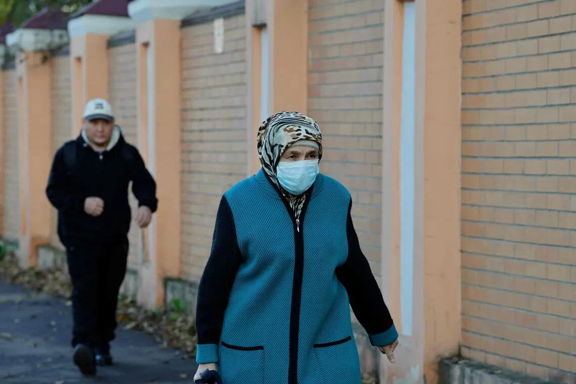 A masked woman walking past the Irkutsk Anti-Plague Research Institute, in the Russian city of Irkutsk, on Oct 7.