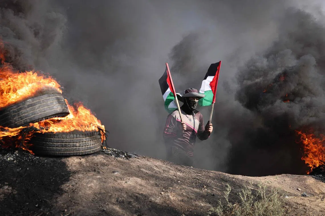 A Palestinian youth burning tyres during a protest by the border fence with Israel east of Gaza City on on July 3, 2023. Israel has stepped up operations in the northern West Bank, home to Jenin city and its adjacent refugee camp, a stronghold of Palestinian armed groups where there has been a spate of attacks on Israelis as well as attacks by Jewish settlers on Palestinian communities. 