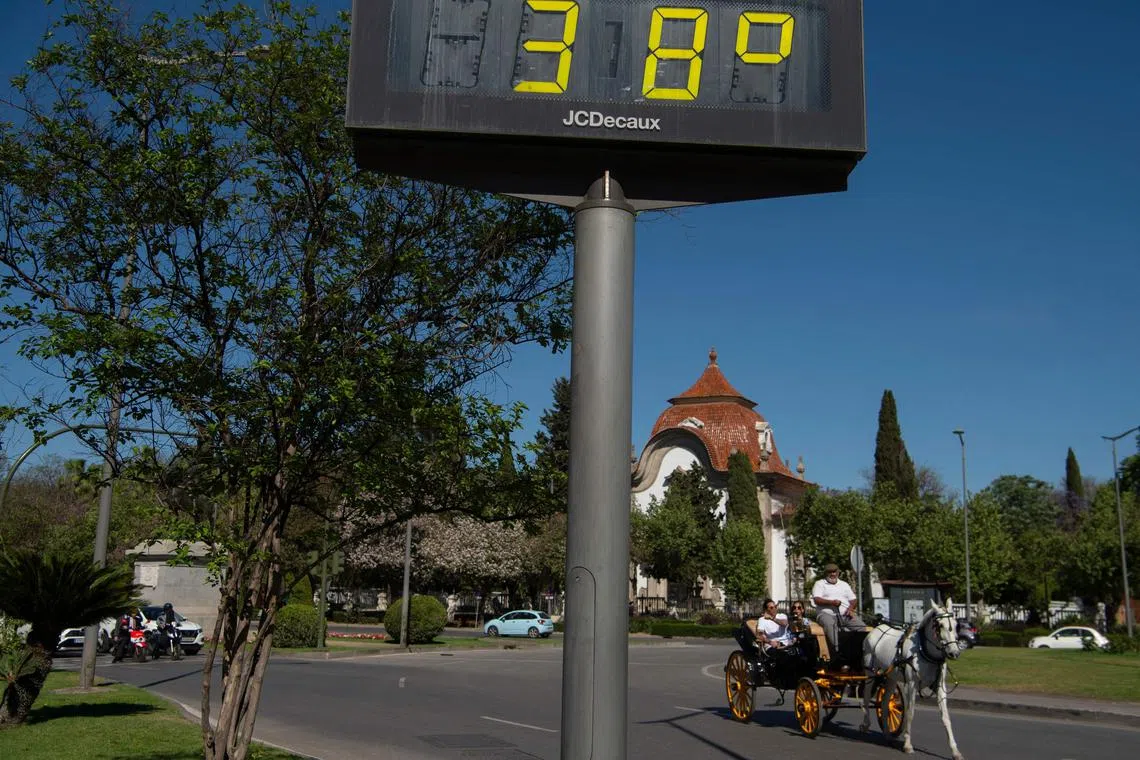 This photograph taken on April 24, 2023 shows a horse-carriage passing next to a street thermometer reading 39 degrees Celsius in Seville as Spain is bracing for an early heat wave. - Drought-hit Spain is bracing for an early heat wave this week with temperatures forecast to hit 40 degrees Celsius (104 Fahrenheit) in some places, another sign of climate change. (Photo by JORGE GUERRERO / AFP)