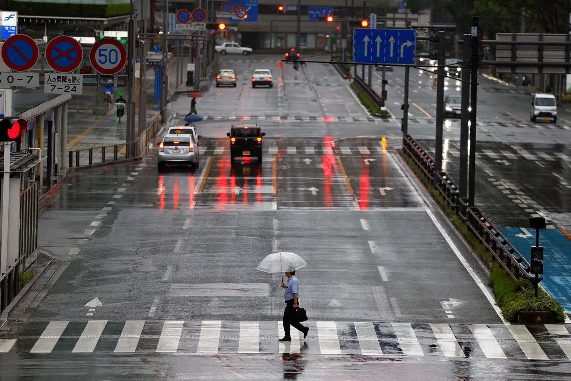 Passersby holding umbrellas walk on the street in the rains and winds caused by Typhoon Shanshan in Fukuoka,  Japan August 30, 2024.  REUTERS/Issei Kato