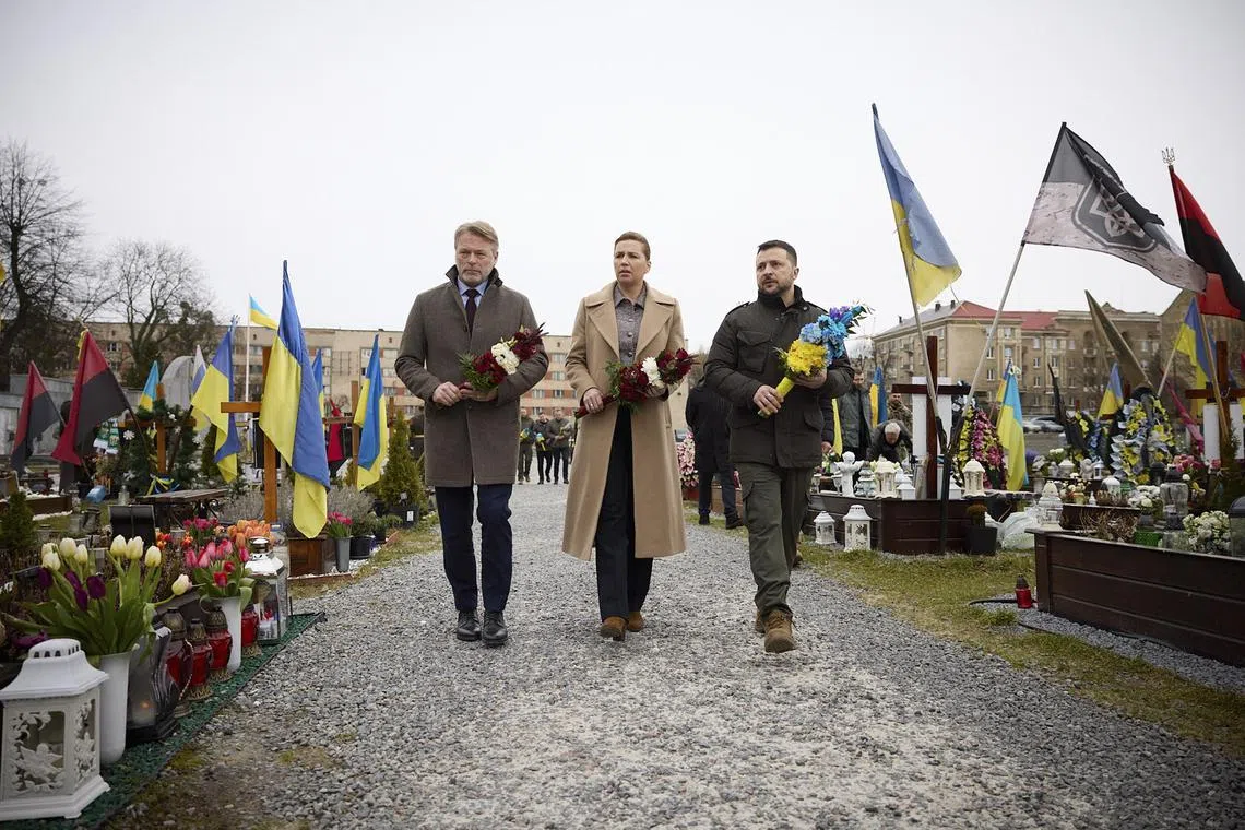 Prime Minister of Denmark Mette Frederiksen (centre) and Ukrainian President Volodymyr Zelenskyy (right) attend a ceremony honoring the memory of fallen defenders at a cemetery in Lviv.