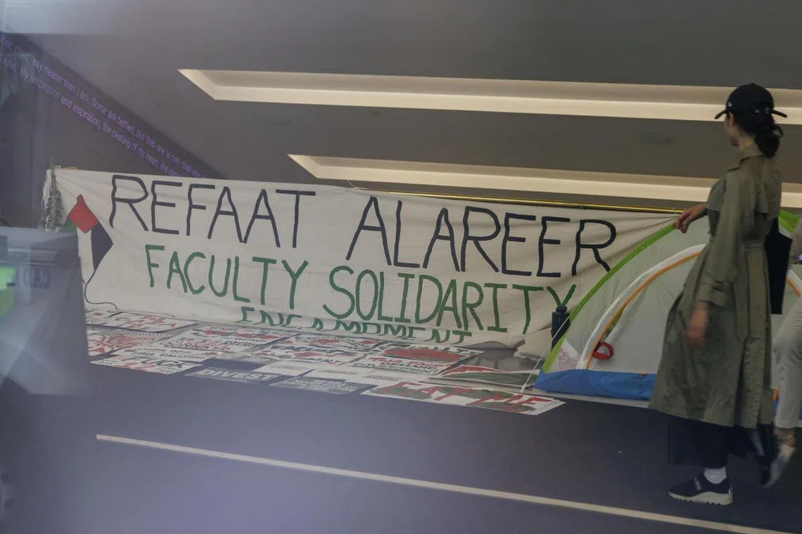 Tents and signs from a faculty encampment seen through the window of The New School in New York on May 9.