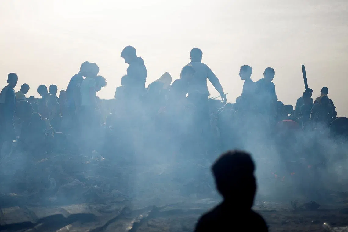 Palestinians search for food among burnt debris in the aftermath of an Israeli strike on an area designated for displaced people, in Rafah in the southern Gaza Strip, May 27, 2024. REUTERS/Mohammed Salem