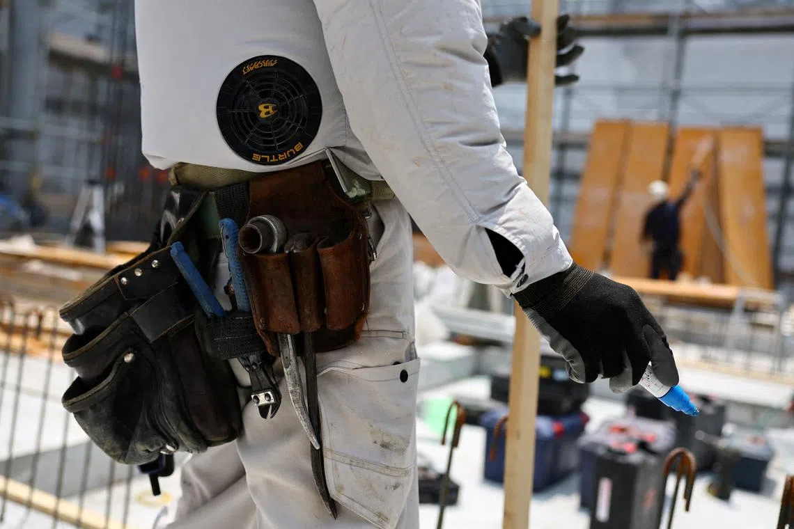 A heat-exposed worker, wearing an air-conditioned jacket which has cooling fans on its back, works at the top of an under-construction apartment building, as the Japanese government issued a heatstroke alert in Tokyo and other prefectures, in Tokyo, Japan July 7, 2025. REUTERS/Issei Kato