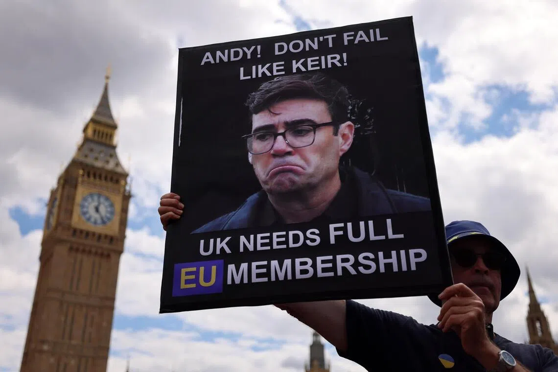 epa13077590 A pro-EU campaigner holds up a sign of Andy Burnham outside Parliament in London, Britain, 01 July 2026. Pro-EU campaigners are hoping prime minister-in-waiting Andy Burnham will seek closer ties to the EU. EPA/ANDY RAIN