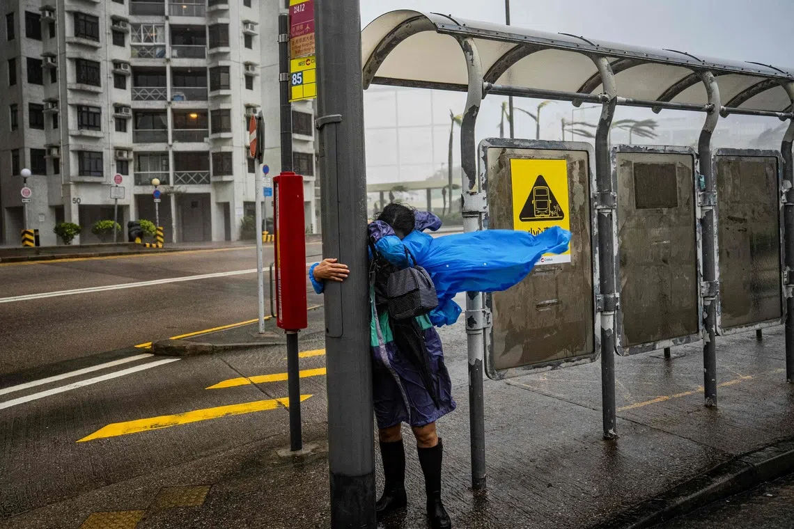 A woman holding on to a lamp post in Hong Kong as Super Typhoon Ragasa hits the city on Sept 24.