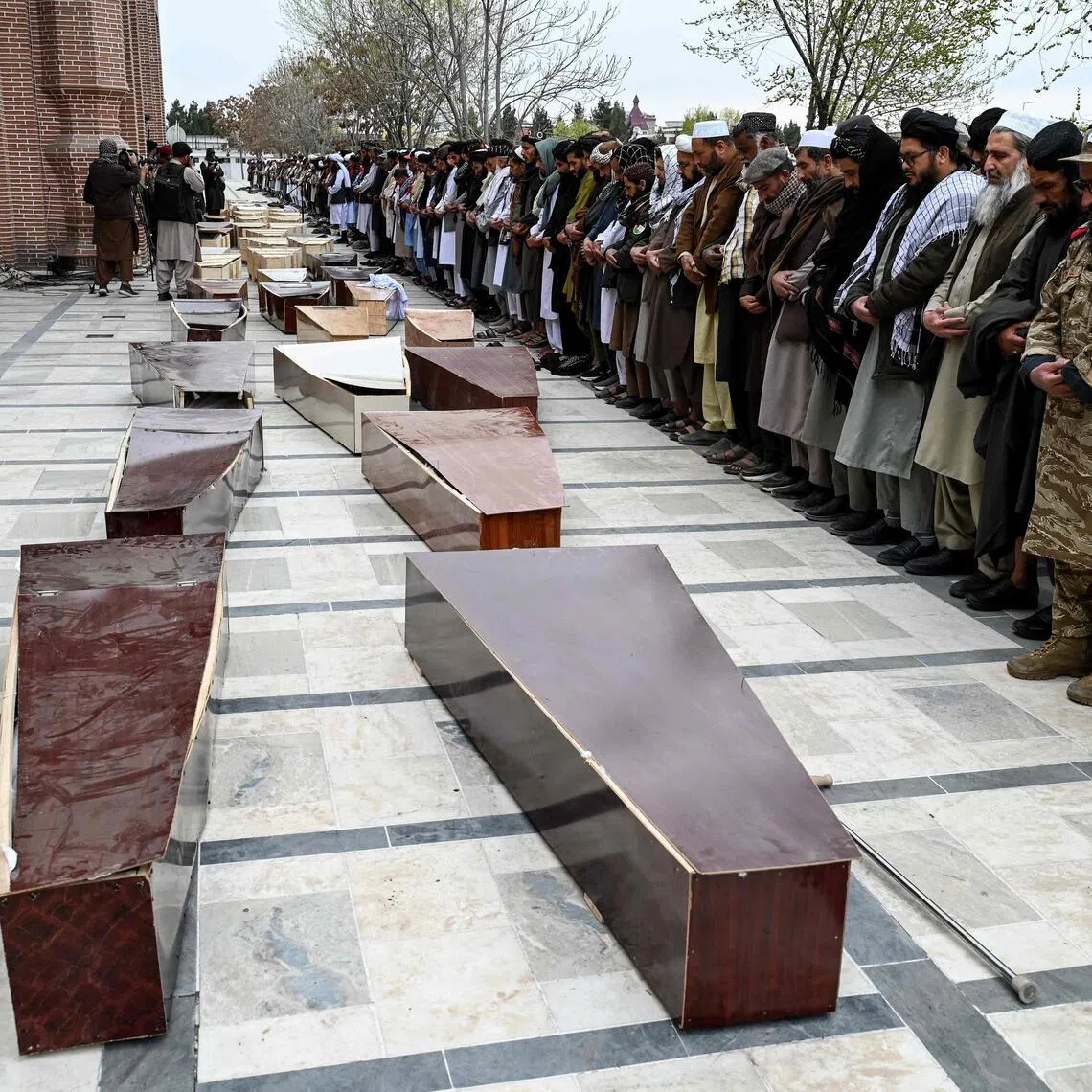 Afghan men offer prayers during the second mass funeral for victims killed by a Pakistani airstrike that struck a drug rehabilitation centre in Kabul.