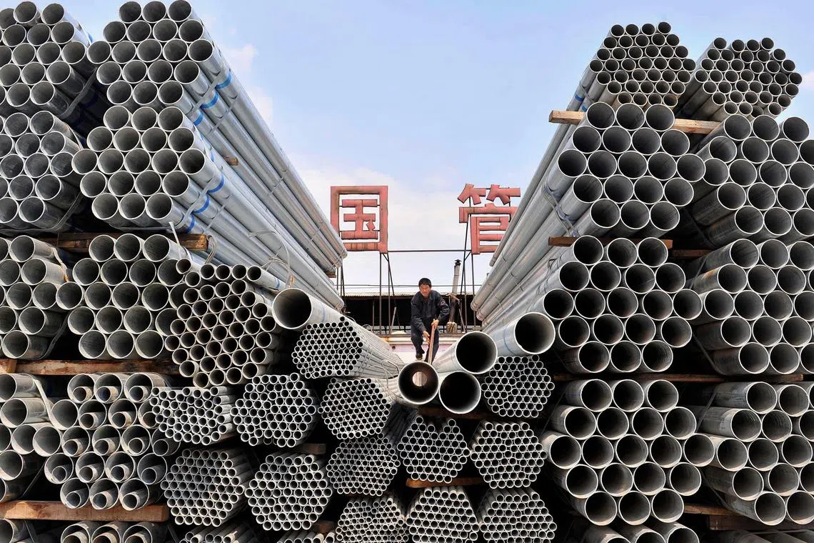 A labourer piles up steel pipes at a steel and iron factory in Shenyang, China, on April 23, 2010. 