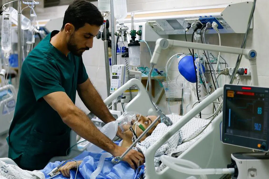 FILE PHOTO: A medical worker assists a Palestinian, who was wounded in Israeli strikes, at the Intensive Care Unit (ICU) of Nasser hospital, as doctors say they are only able to accept critical cases that are in need of surgery, while the unit is filled up with victims of the ongoing conflict with Israel, in Khan Younis, in the southern Gaza Strip, October 26, 2023. REUTERS/Ibraheem Abu Mustafa/File photo