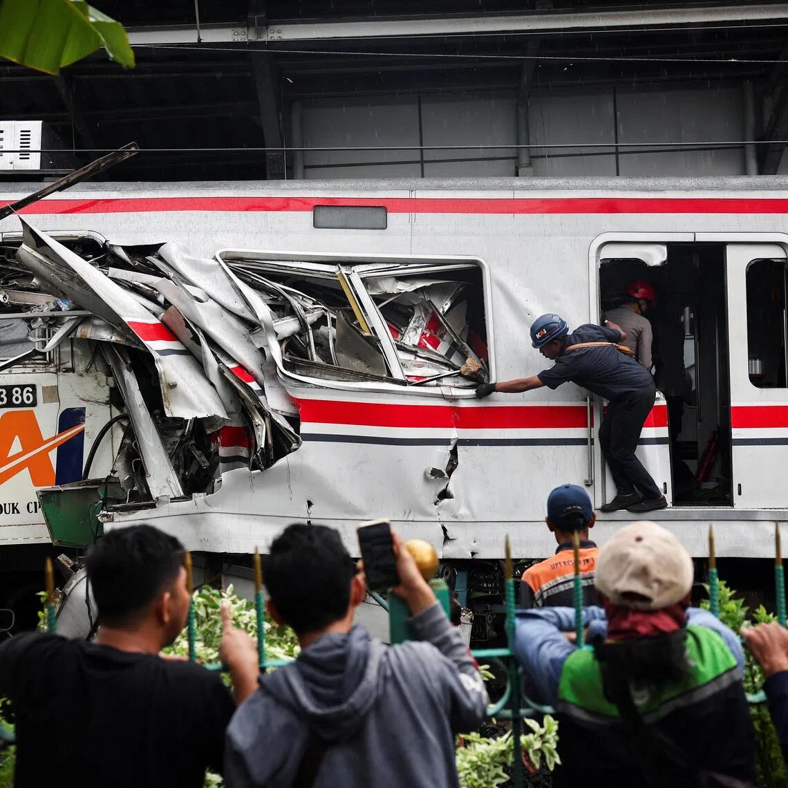 People watch as a technician works at the site after a deadly collision between a commuter line train and a long-distance train, in Bekasi, on the outskirts of Jakarta on April 28.