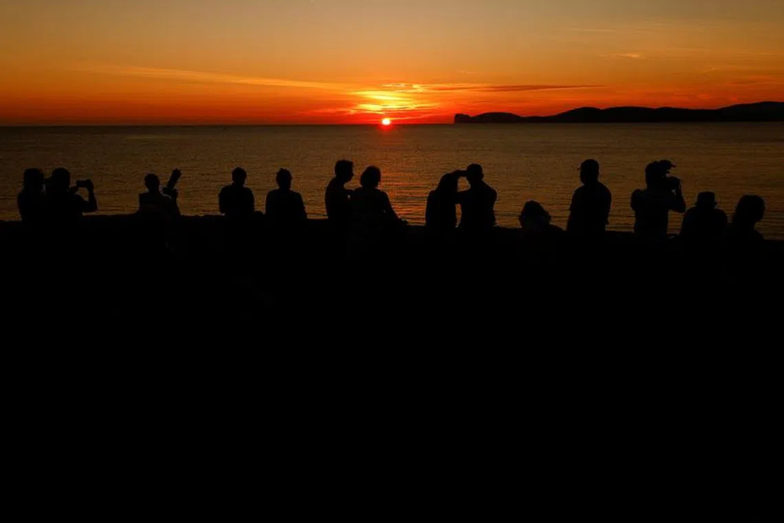 File photo: People enjoy sunset in Alghero, Italy, October 3, 2021. REUTERS/Guglielmo Mangiapane/File photo