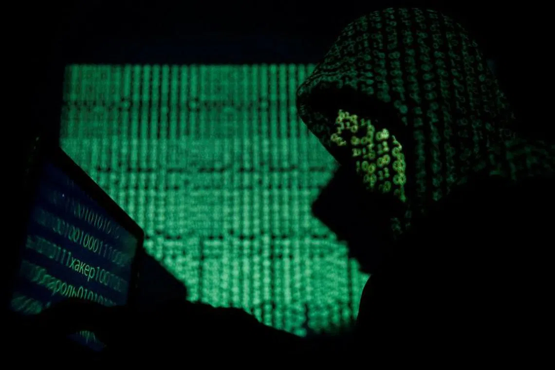 FILE PHOTO: A hooded man holds a laptop computer as cyber code is projected on him in this illustration picture taken on May 13, 2017. REUTERS/Kacper Pempel/Illustration/File Photo