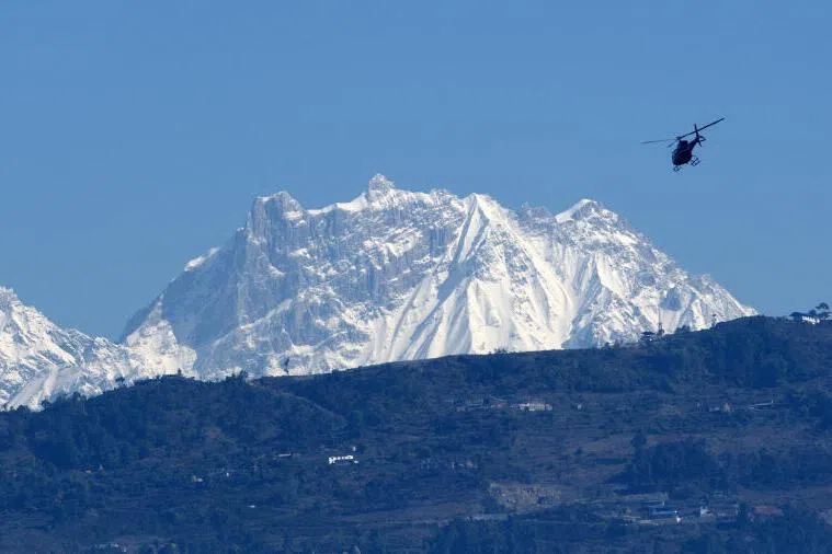 A helicopter flies with rescue team in front of the Annapurna mountain range, in Pokhara, some 200 km west of Kathmandu on January 22, 2020.
