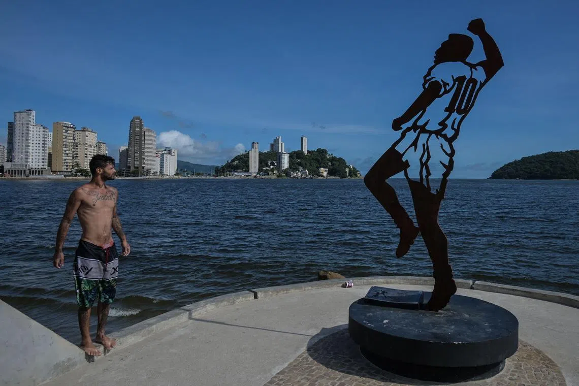 A man looking at a statue depicting Brazilian football legend Pele, design by Brazilian artist Luis Costa, at Rei Pele pier, in Sao Vicente, coast of Sao Paulo state, Brazil, on Dec 19, 2023. 