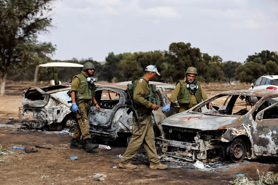 FILE PHOTO: Israeli soldiers inspecting the burnt cars of festival-goers at the site of an attack on the Nova Festival by Hamas gunmen, on Oct 13, 2023. 