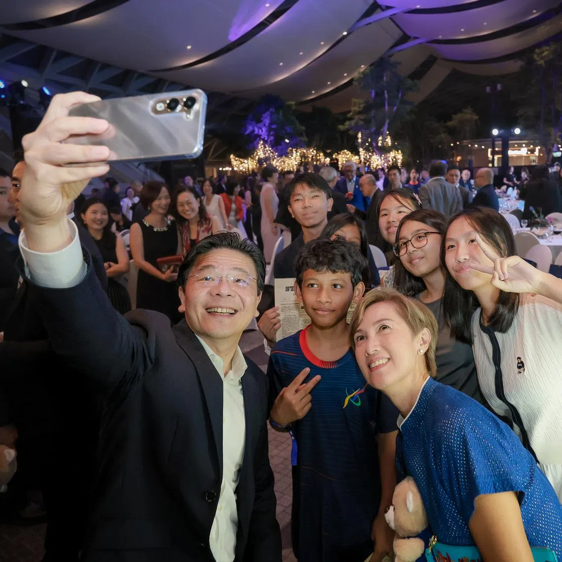 PM Lawrence Wong taking a wefie with Minister for Minister for Digital Development and Information Josephine Teo and The Straits Times School Pocket Money Fund beneficiaries during a gala dinner on July 11 to commemorate ST’s 180th anniversary.