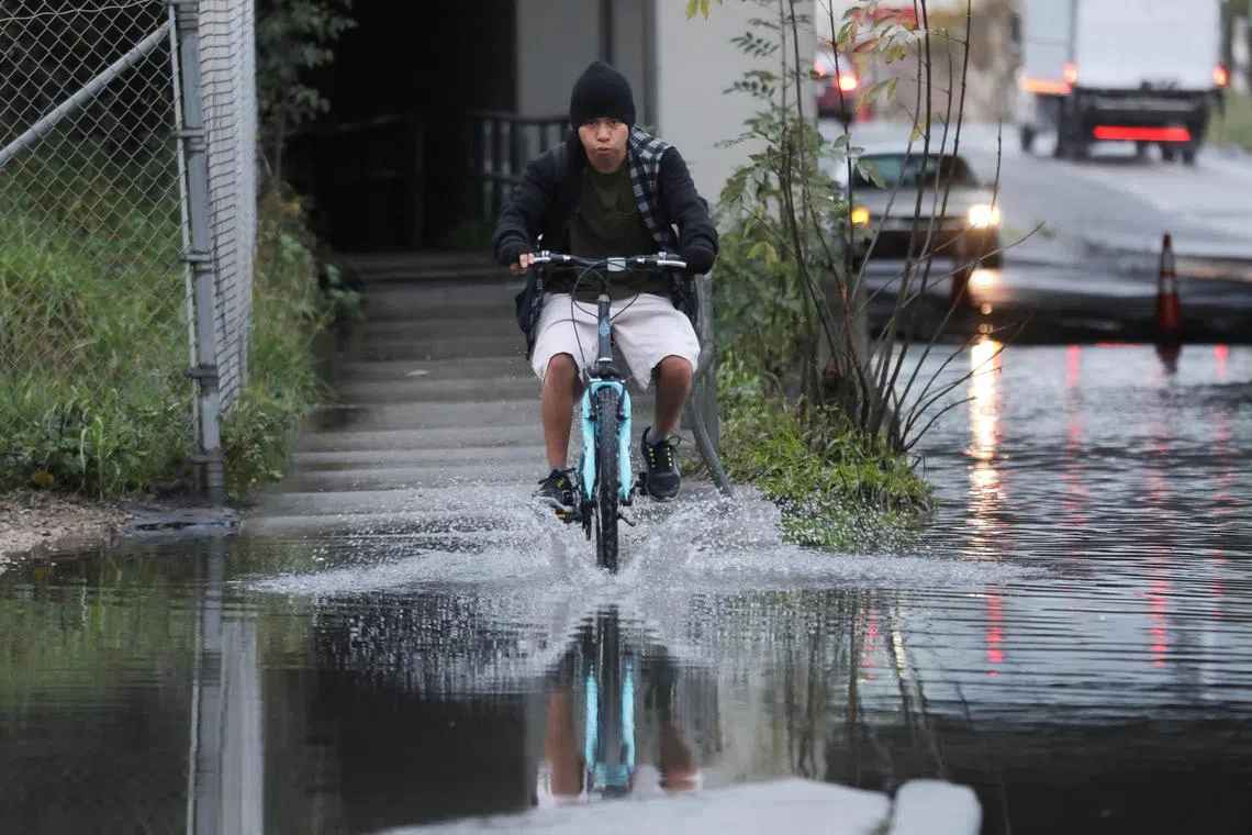 A cyclist rides along a flooded sidewalk, after an atmospheric river storm system struck in Hayward, California, on March 10, 2023.