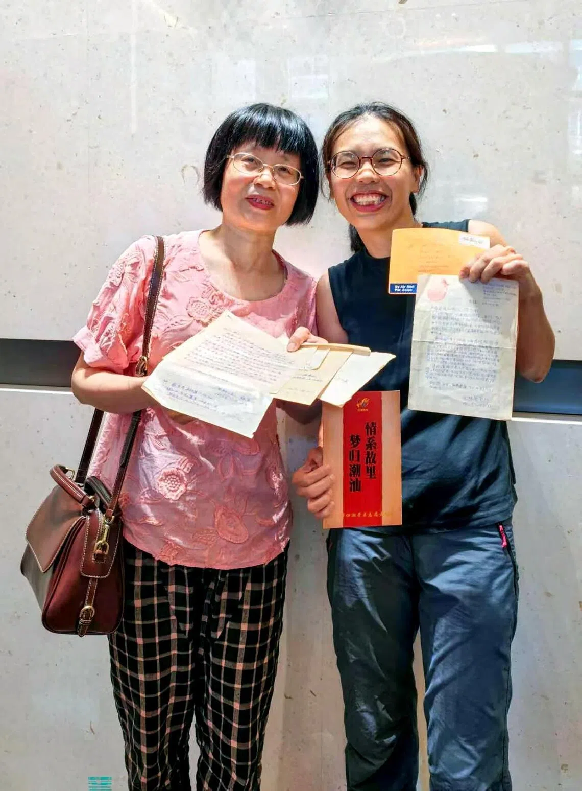 Jasmine Goh-Chew (right) with her first cousin whom she was reunited with, holding letters that they had written to each other’s families on behalf of their elders more than 30 years ago.