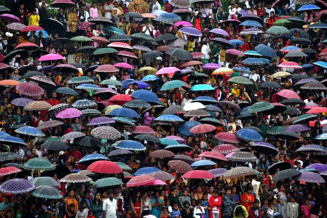 TOPSHOT - Spectators carrying umbrellas gather during the annual Behdienkhlam festival which is celebrated annually after the sowing period in Tuber village in India's north-eastern state of Meghalaya on July 17, 2023. (Photo by Biju BORO / AFP)