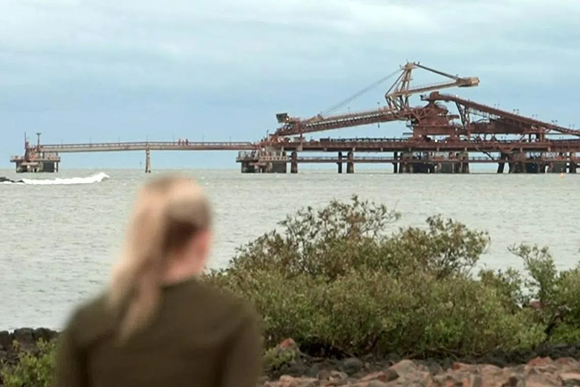 This frame grab taken from video footage provided by Australian Broadcast Corporation (ABC) on February 13, 2025 via AFPTV shows a local walking near wharfs that are part of mining operations at Port Hedland, ahead of the arrival of category five Cyclone Zelia. Forecasters said the slow-moving, severe tropical cyclone was moving south on February 13 morning towards Port Hedland -- one of the world's busiest iron ore loading ports -- with landfall expected in the afternoon. (Photo by Handout / ABC / AFP) / - Australia OUT / RESTRICTED TO EDITORIAL USE - MANDATORY CREDIT "AFP PHOTO /  AUSTRALIAN BROADCASTING CORPORATION (ABC)" - NO MARKETING NO ADVERTISING CAMPAIGNS - DISTRIBUTED AS A SERVICE TO CLIENTS