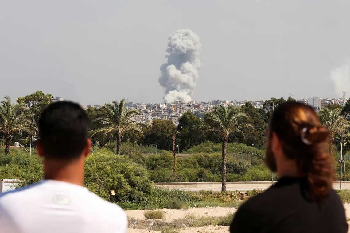 People watch as smoke billows over southern Lebanon following Israeli strikes, as seen from Tyre, southern Lebanon on Sept 23.