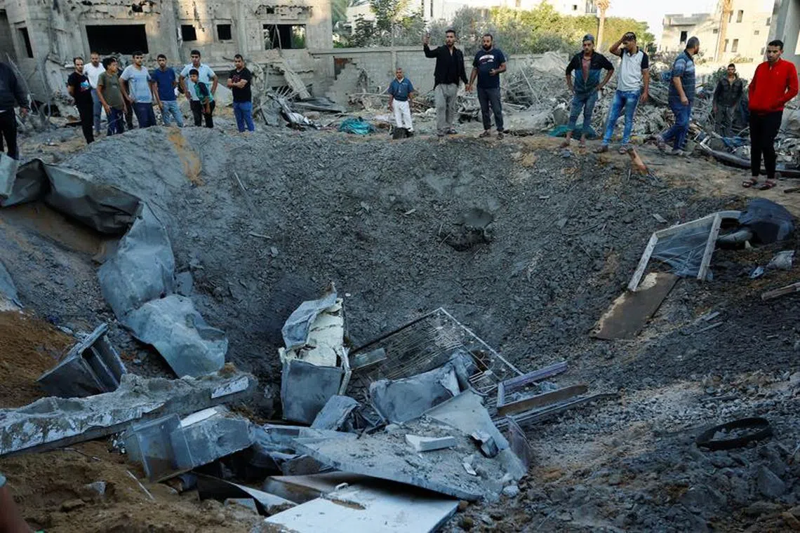 Palestinians look at the rubble of a house destroyed in Israeli strikes amid the conflict with Israel in Khan Younis, in the southern Gaza Strip, October 12, 2023. REUTERS/Ibraheem Abu Mustafa