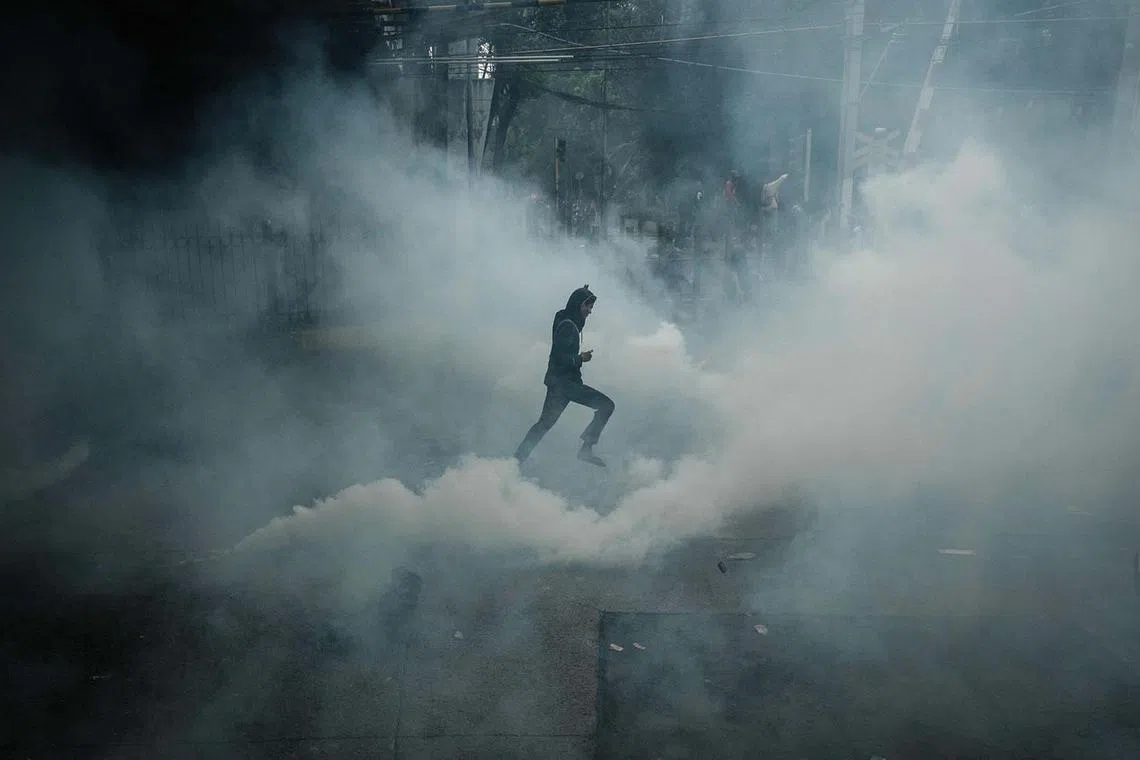 A demonstrator running through tear gas during a labour union protest for improving working conditions, near the Parliament in Jakarta on Aug 28, 2025. 