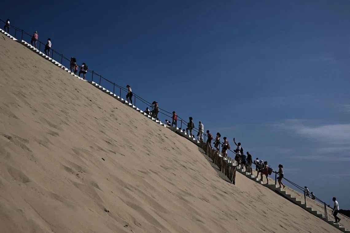 Visitors walking the stairs of the dune of Pilat, the tallest sand dune in Europe, in Pyla sur Mer, southwestern France, on July 9, 2023. 